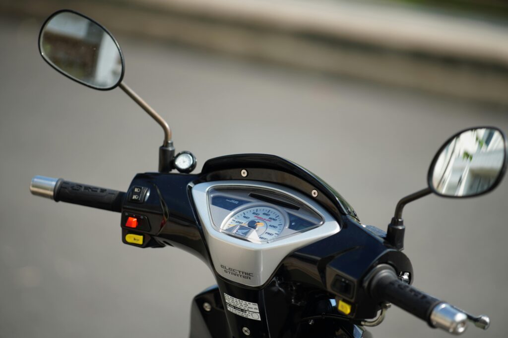 Detailed view of electric scooter handlebars, highlighting the dashboard, mirrors, and controls.